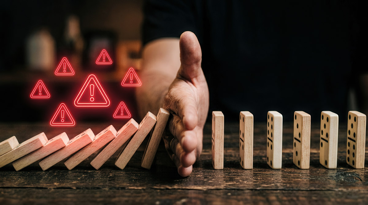 Application security A hand stopping a line of brown falling dominoes